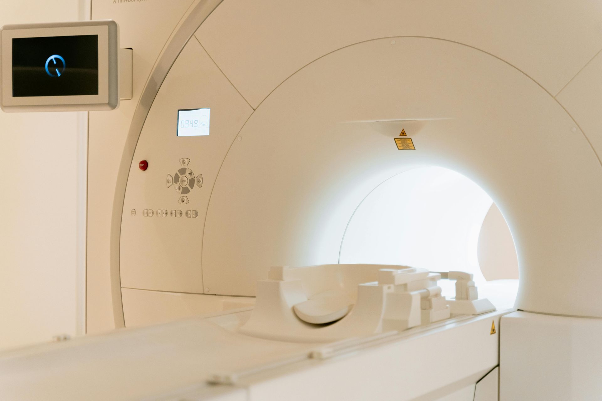 Une machine IRM est installée dans une pièce avec un moniteur sur le mur.