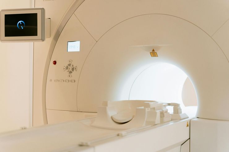 Une machine IRM est installée dans une pièce avec un moniteur sur le mur.