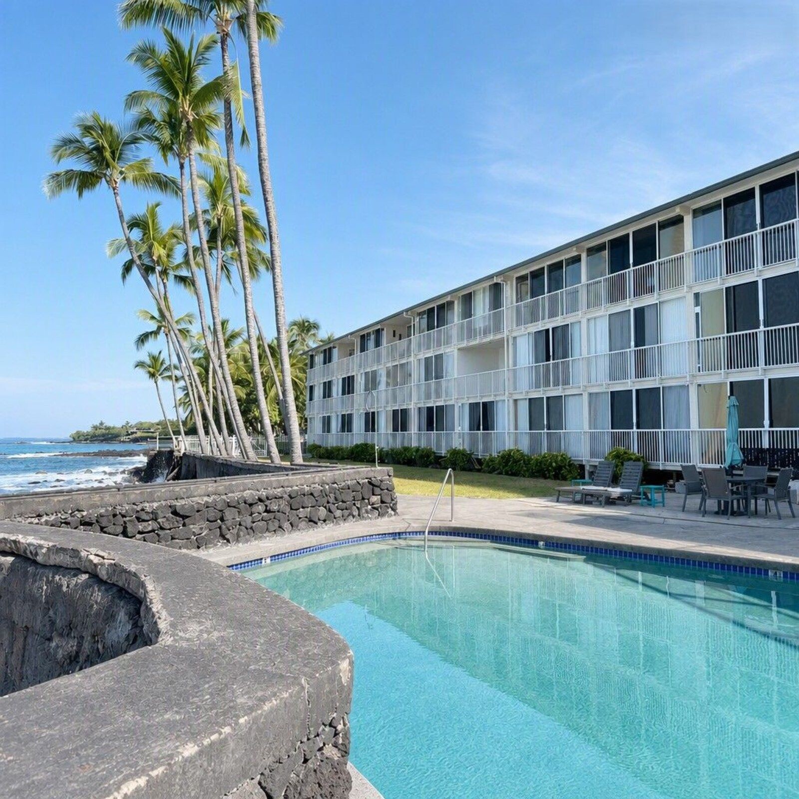 Oceanfront pool at Kona Magic Sands with palms and the ocean beyond