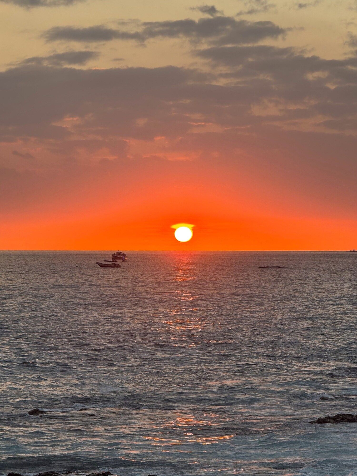 Sunset over the ocean with a boat on the horizon