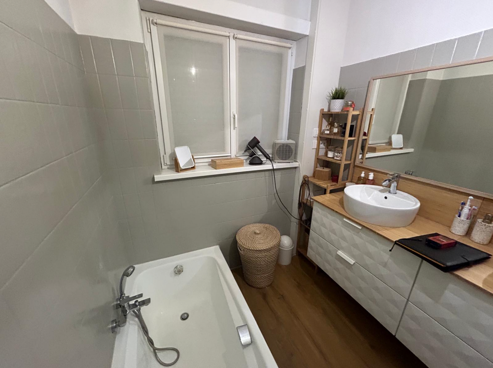 Une salle de bain avec baignoire, lavabo, miroir et fenêtre.