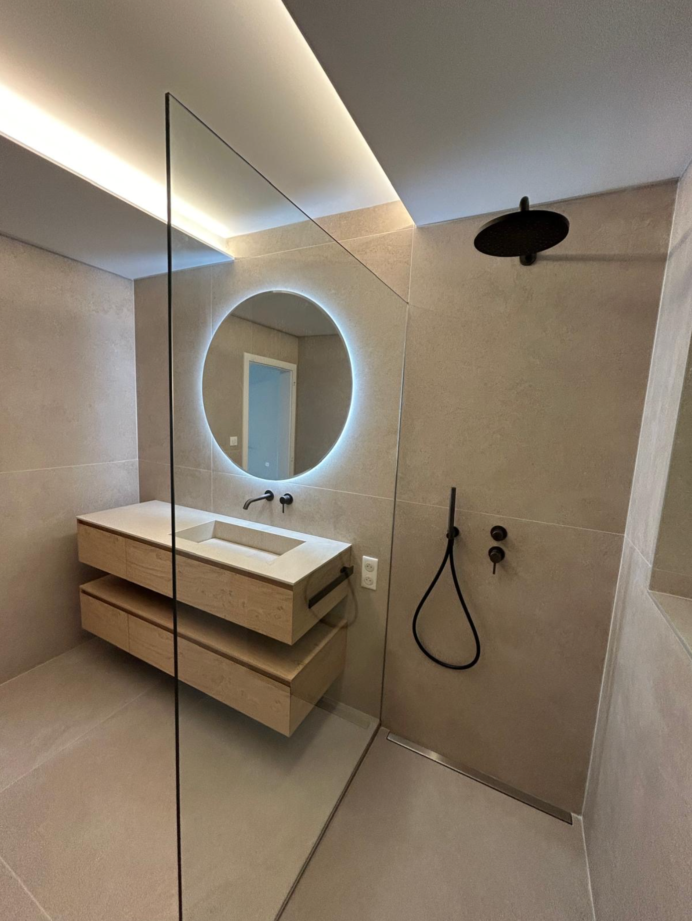 Une salle de bain avec lavabo, miroir et douche.