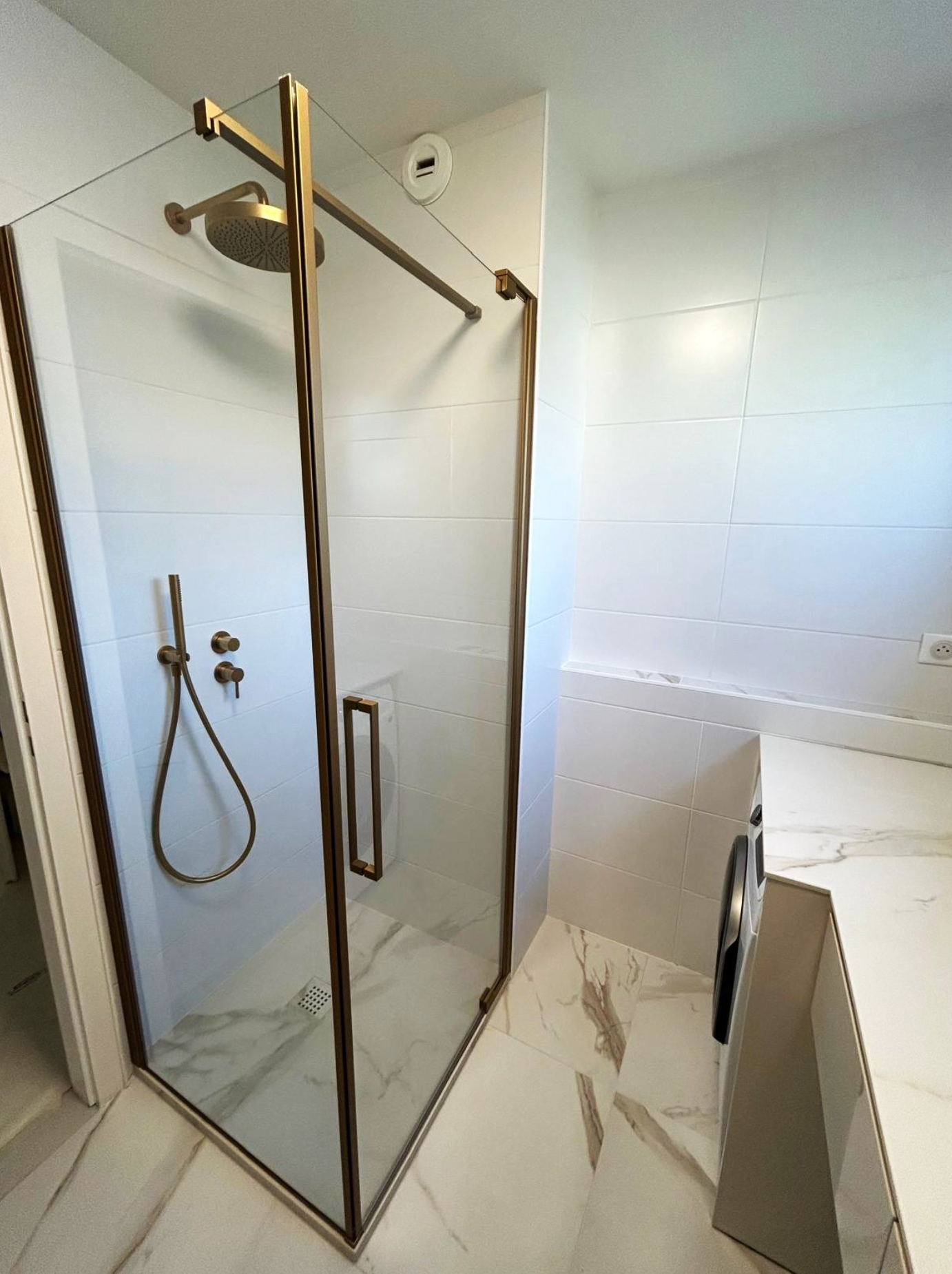 Une salle de bain avec douche à l'italienne et machine à laver
