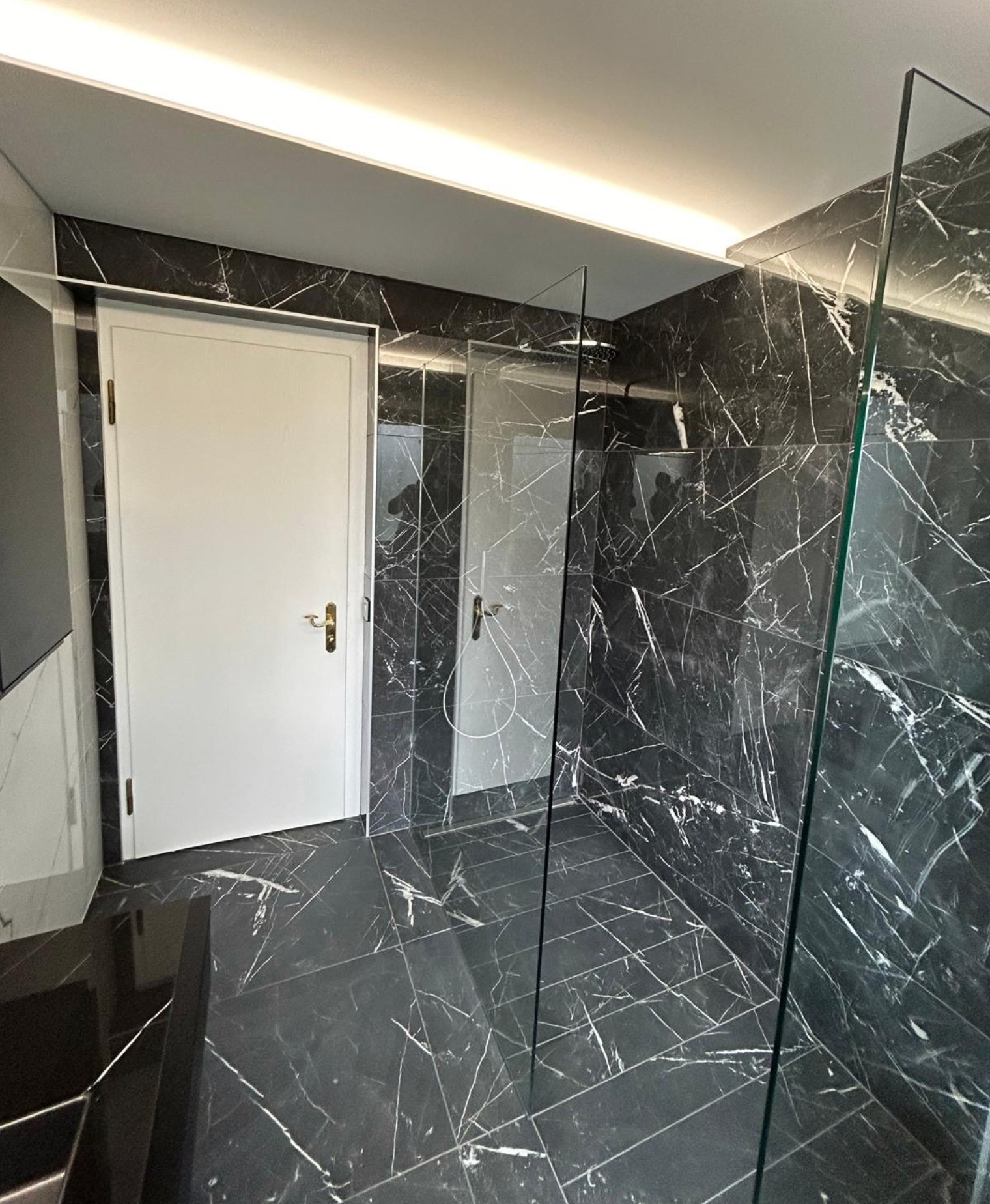 Une salle de bain avec des murs en marbre noir et une douche à l'italienne.