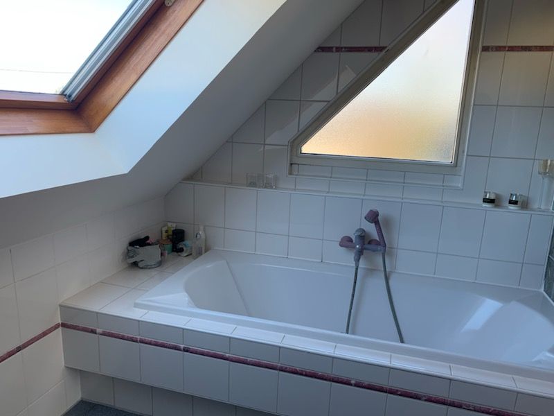Une baignoire dans une salle de bain avec une lucarne au-dessus