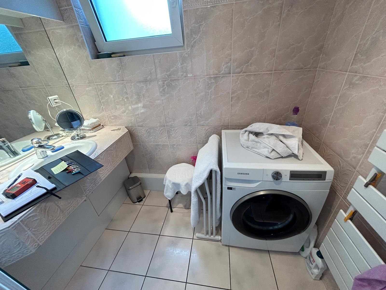 Une salle de bain avec une machine à laver et un lavabo.