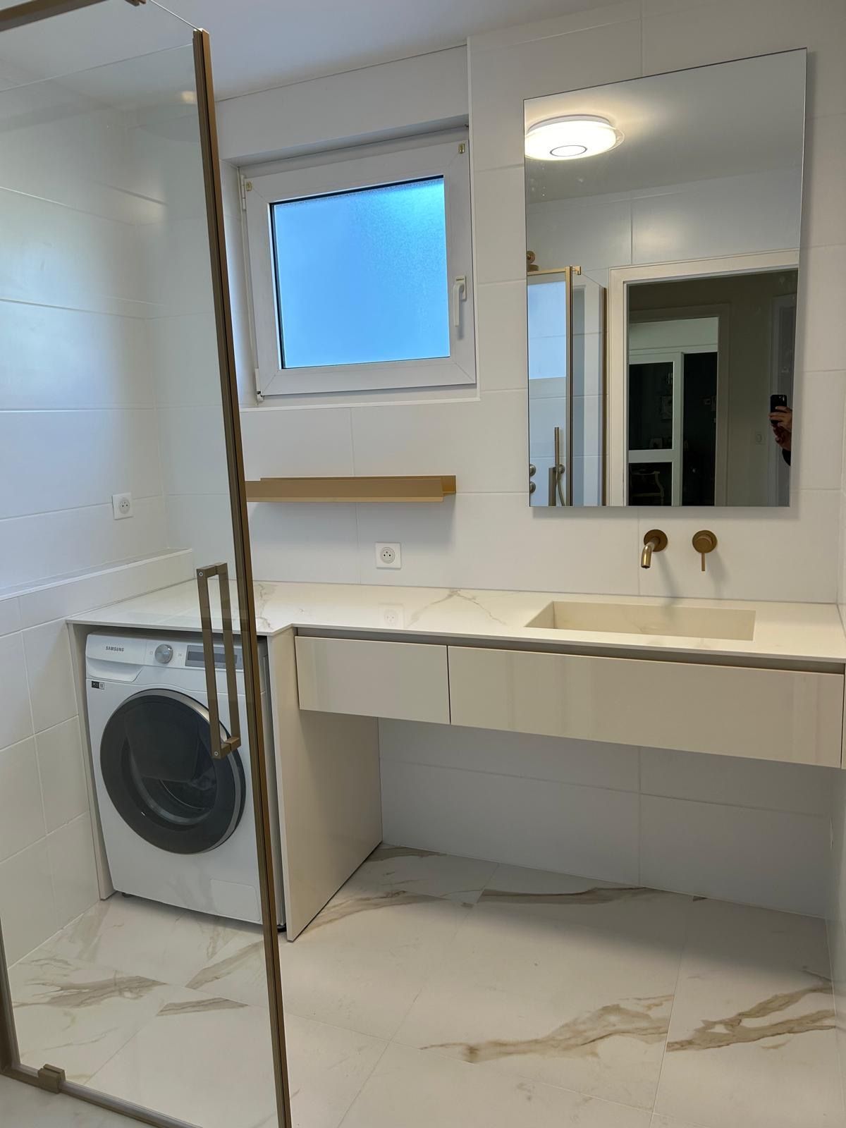 Une salle de bain avec laveuse, sécheuse et un lavabo
