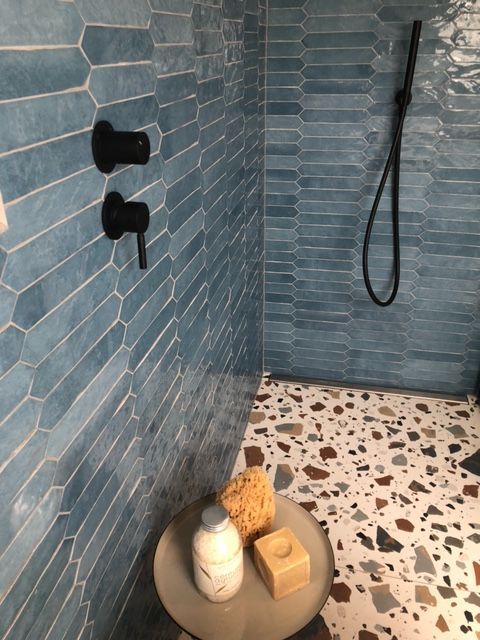 Une salle de bain avec carrelage bleu et sol en terrazzo