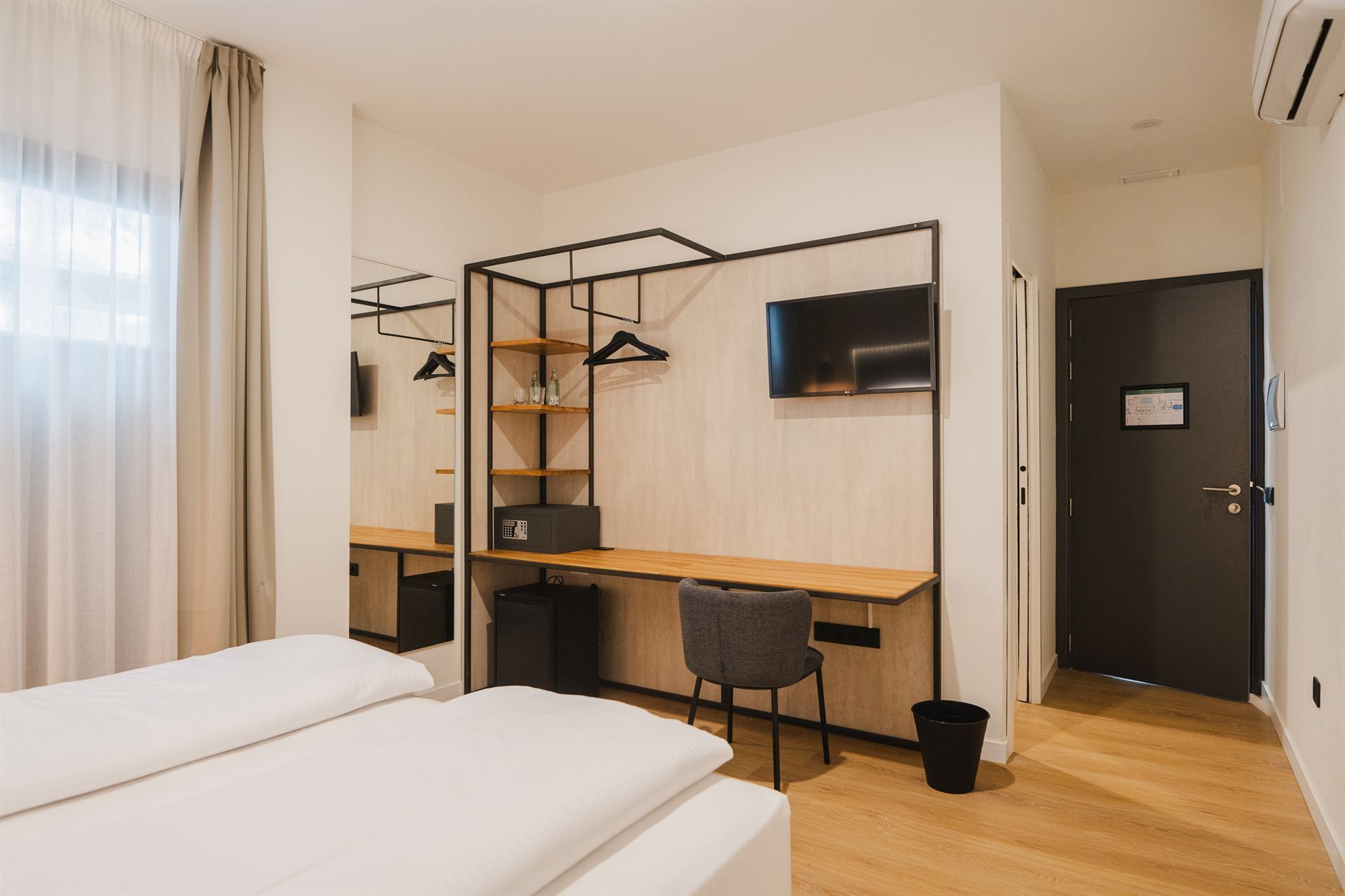 A hotel room with a bed , desk , chair and television.