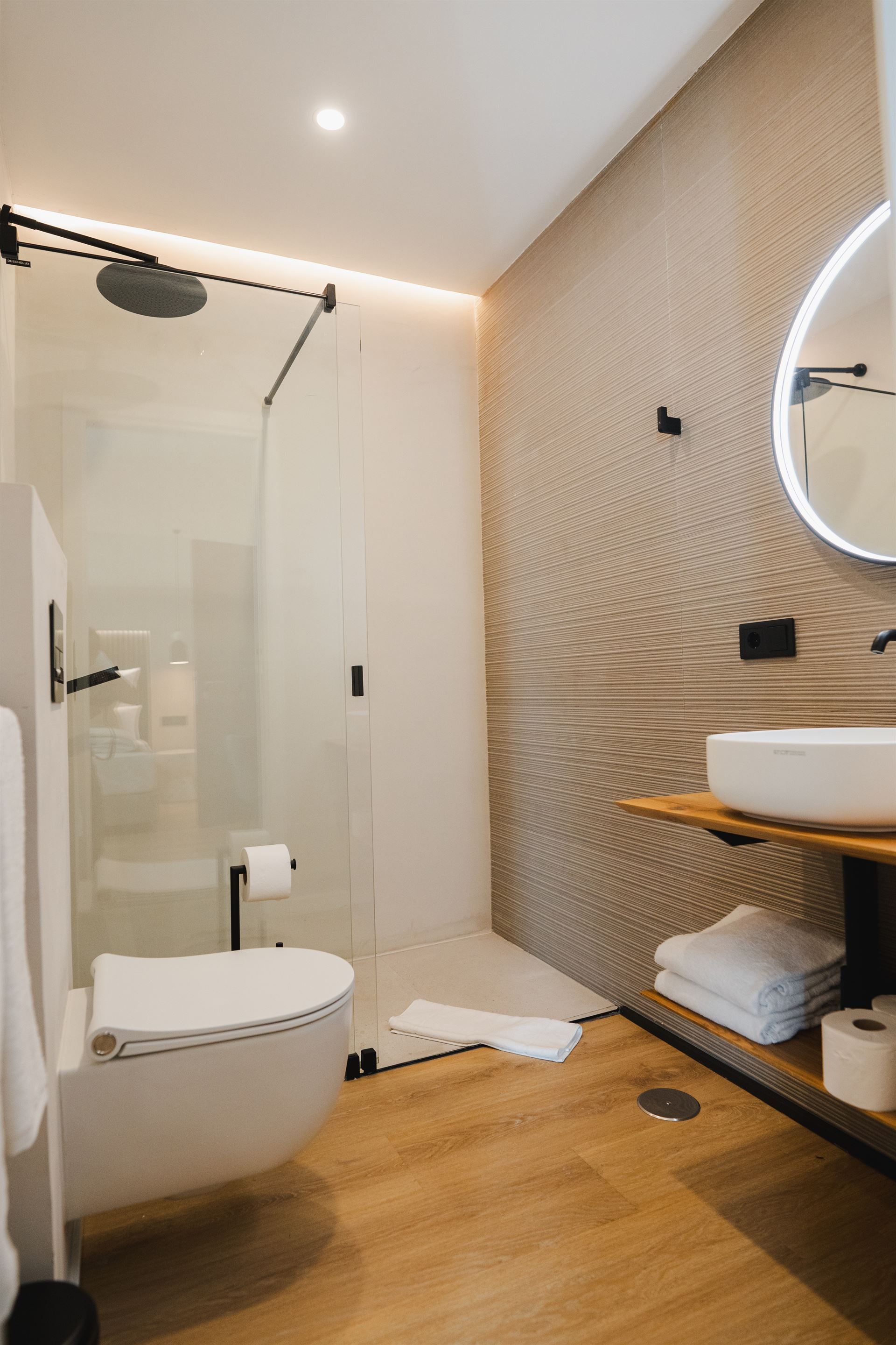 A bathroom with a toilet , sink , shower and mirror.