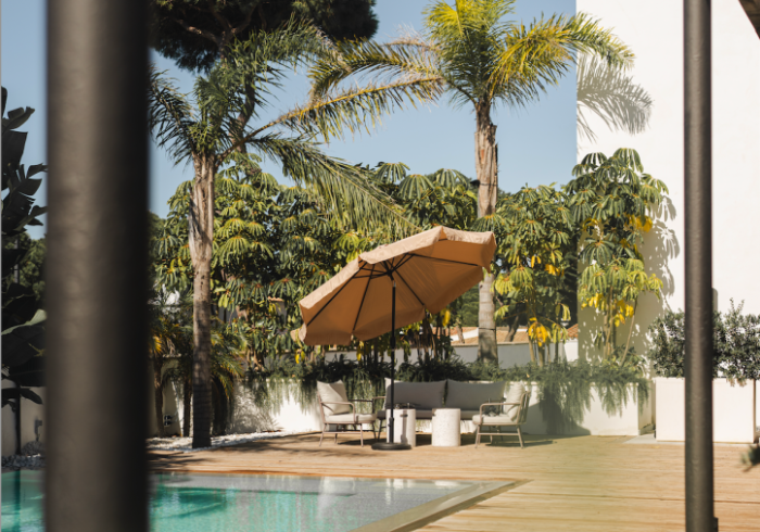 A swimming pool with a table and chairs under an umbrella.
