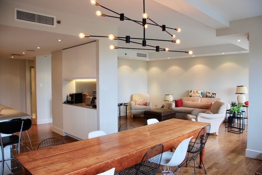 Espace de vie ouvert avec table à manger, coin salon et éclairage moderne par un lustre.