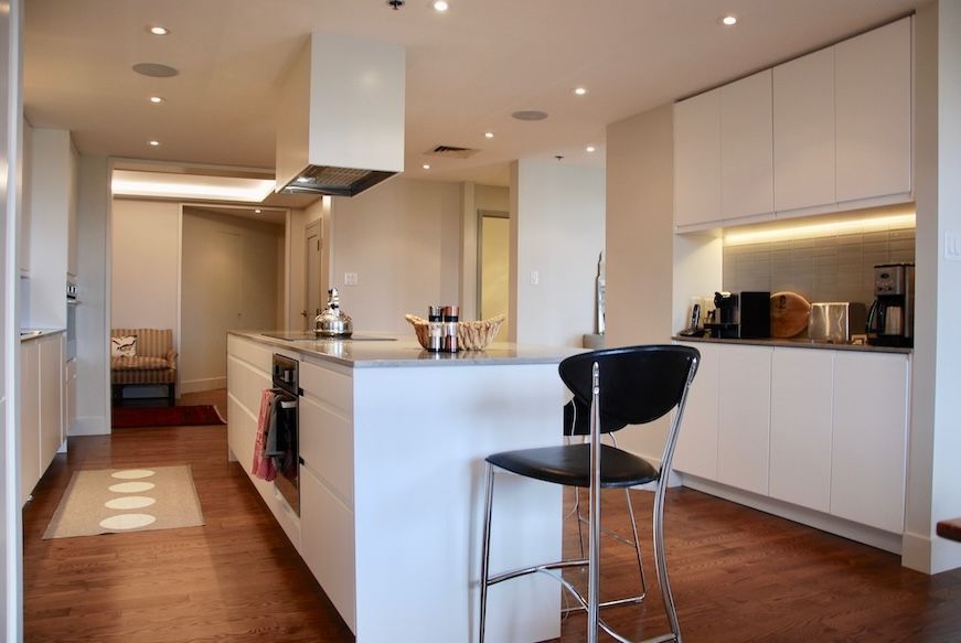 Cuisine moderne blanche avec îlot central, parquet et tabouret de bar.