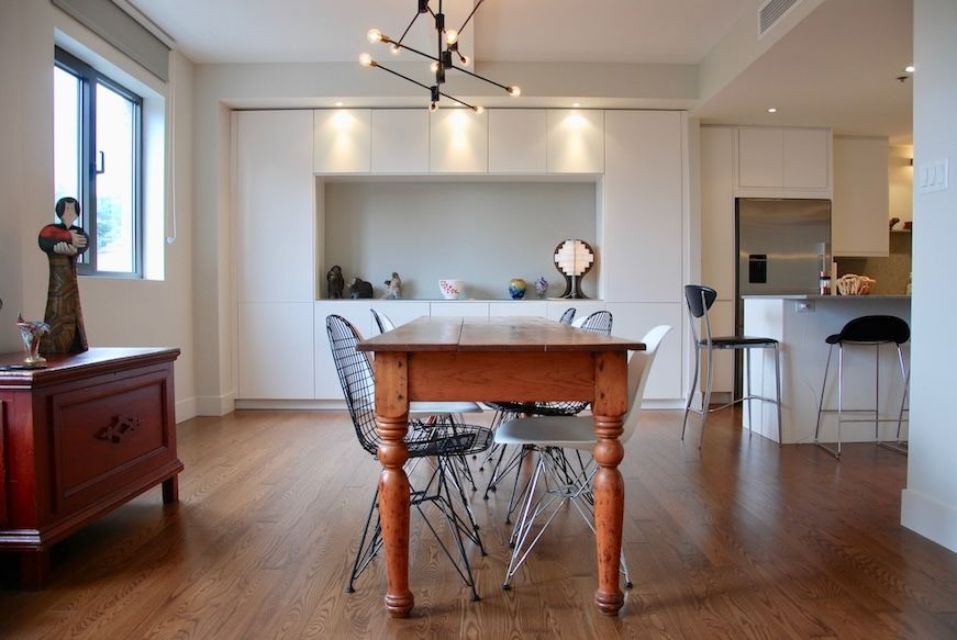 Salle à manger avec table en bois et chaises dépareillées, étagères intégrées, parquet.