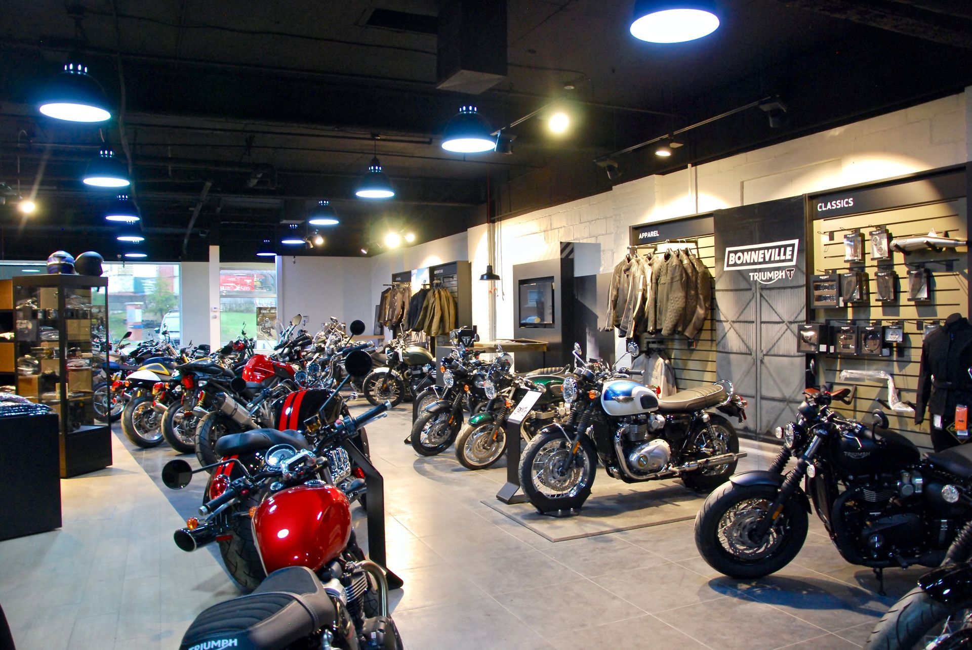 Intérieur d'un showroom de motos présentant plusieurs modèles exposés, ainsi que des vêtements et des accessoires.