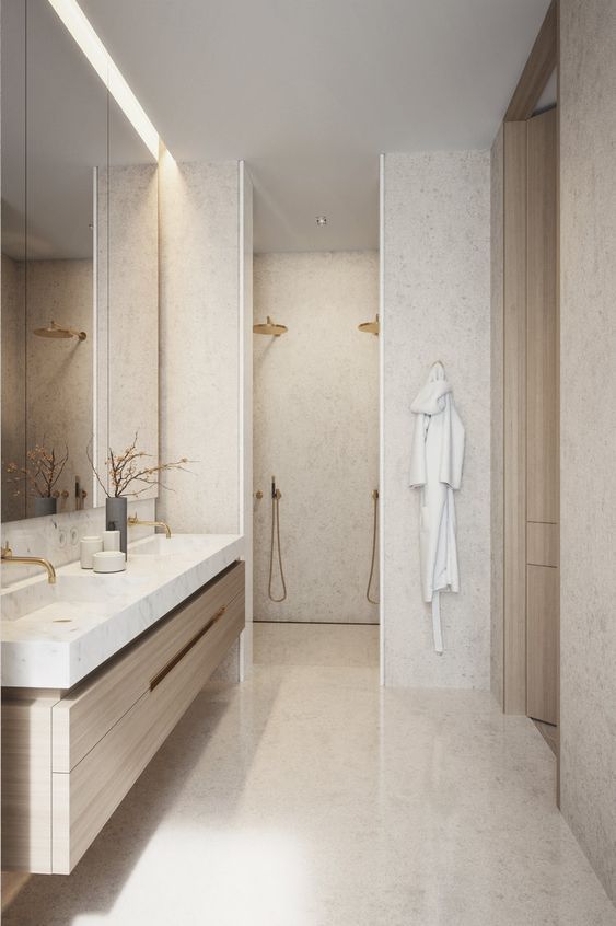 Salle de bains moderne avec meuble-lavabo en bois clair, comptoir en marbre, douche à l'italienne et peignoir accroché au mur.