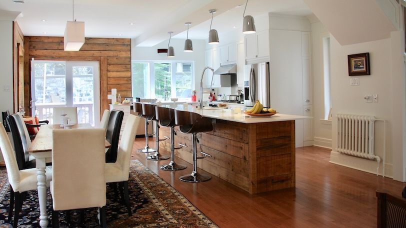 Cuisine avec un îlot en bois, des placards blancs et une table à manger avec des chaises.