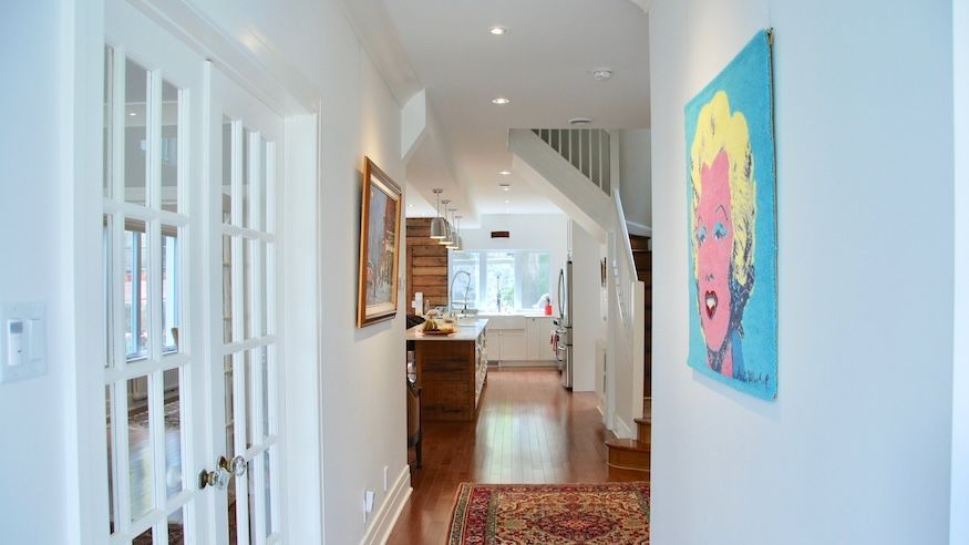 Couloir avec murs blancs, parquet, portes-fenêtres et un tableau pop art de Marilyn Monroe.