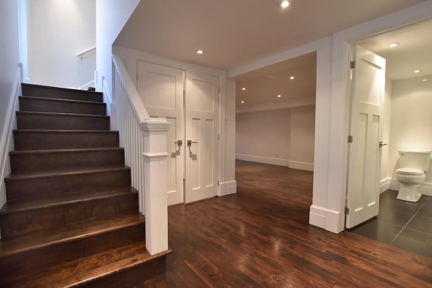 Escalier en bois menant à un sous-sol avec portes, rangements intégrés et salle de bains.