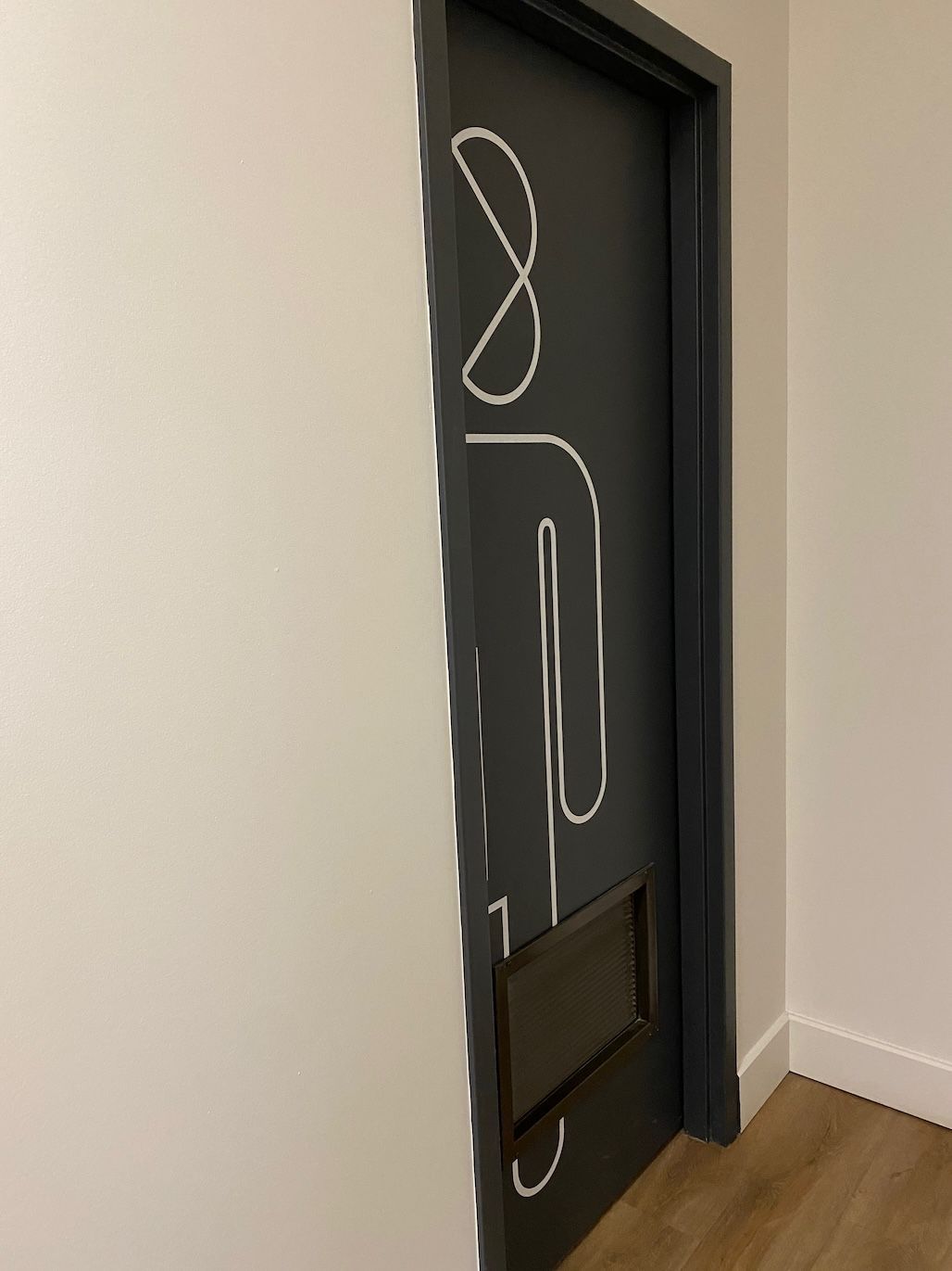 Porte sombre avec un symbole de toilettes aux contours blancs ; boîte noire en bas.
