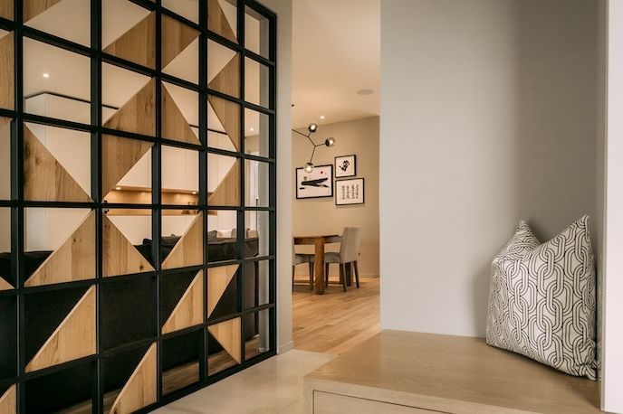 Intérieur moderne avec cloison géométrique en bois et métal noir.