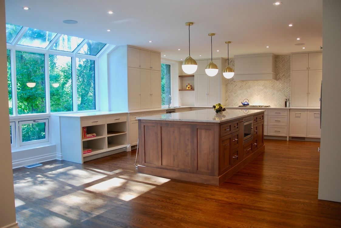 Cuisine moderne avec parquet, îlot central, placards blancs et grandes fenêtres.