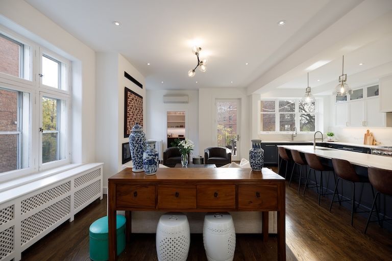 Intérieur spacieux et décloisonné avec parquet. La cuisine et le séjour sont agrémentés d'une longue table en bois ornée de vases bleus et blancs.
