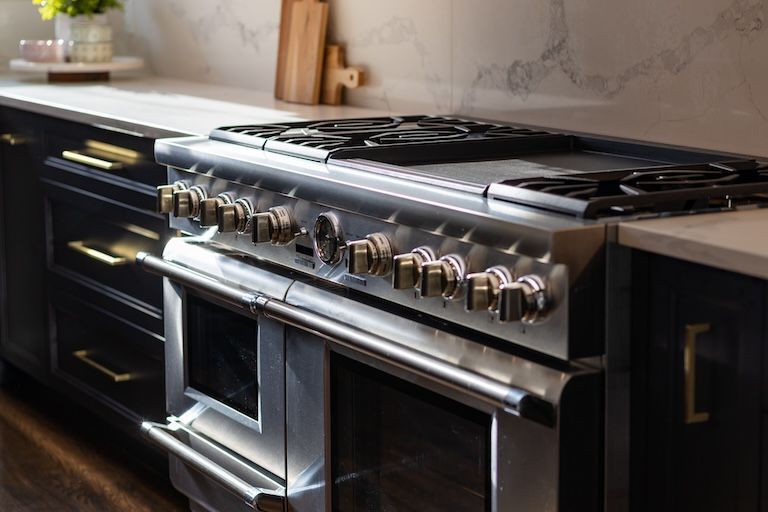 Four en acier inoxydable avec boutons en laiton dans une cuisine moderne.