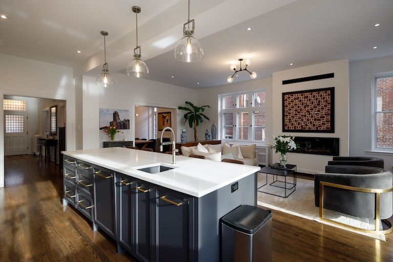 Cuisine moderne avec îlot central, coin salon, parquet et cheminée.