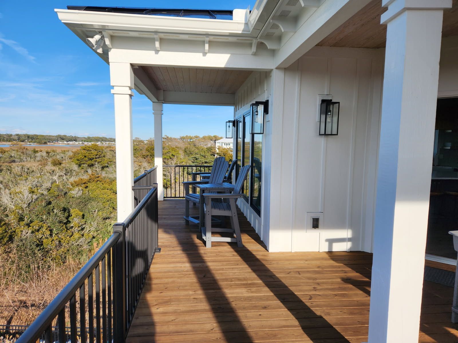A wooden deck with chairs and a railing on a house