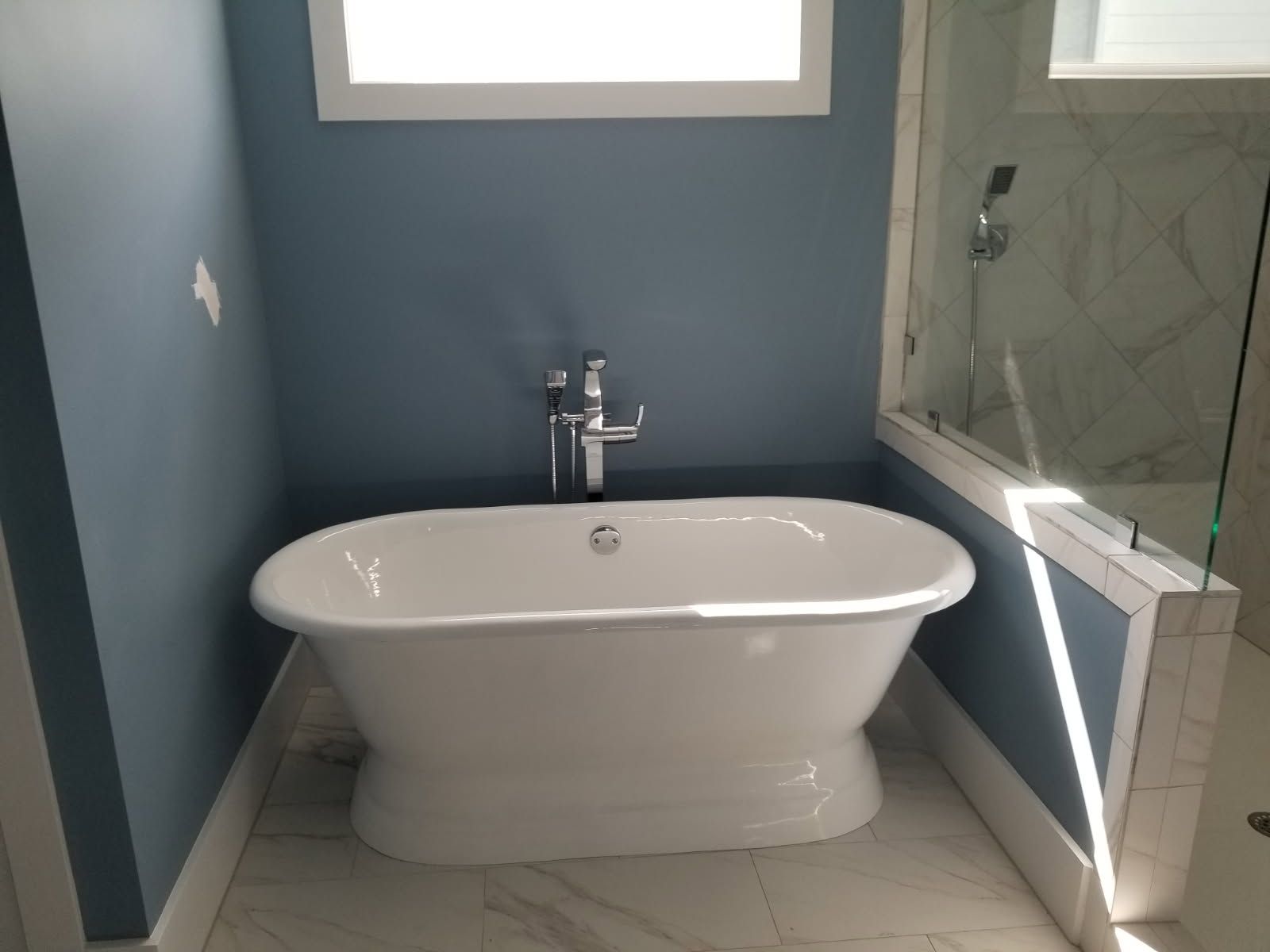A white bathtub in a bathroom with blue walls