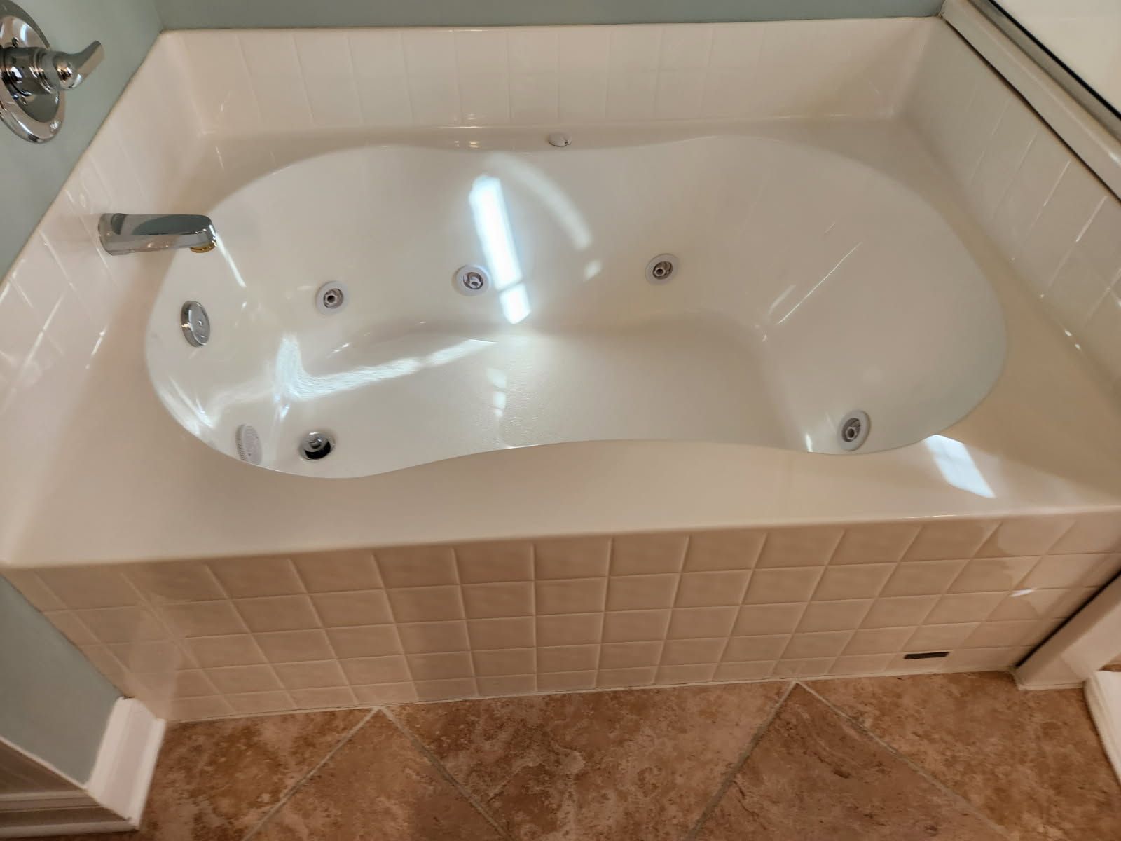 A white bathtub is sitting on a tiled floor in a bathroom.