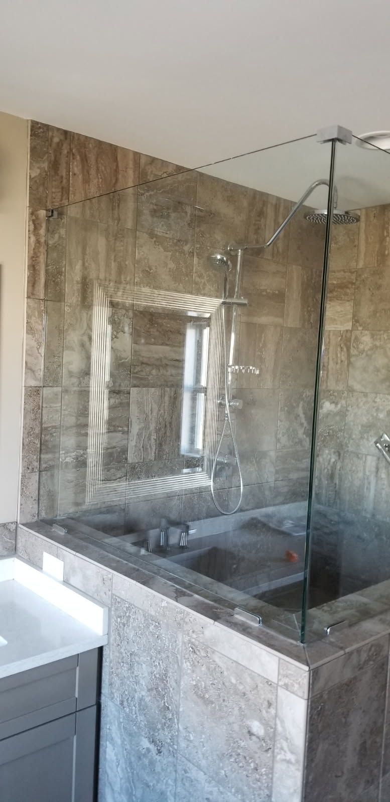A bathroom with a walk in shower and a sink.