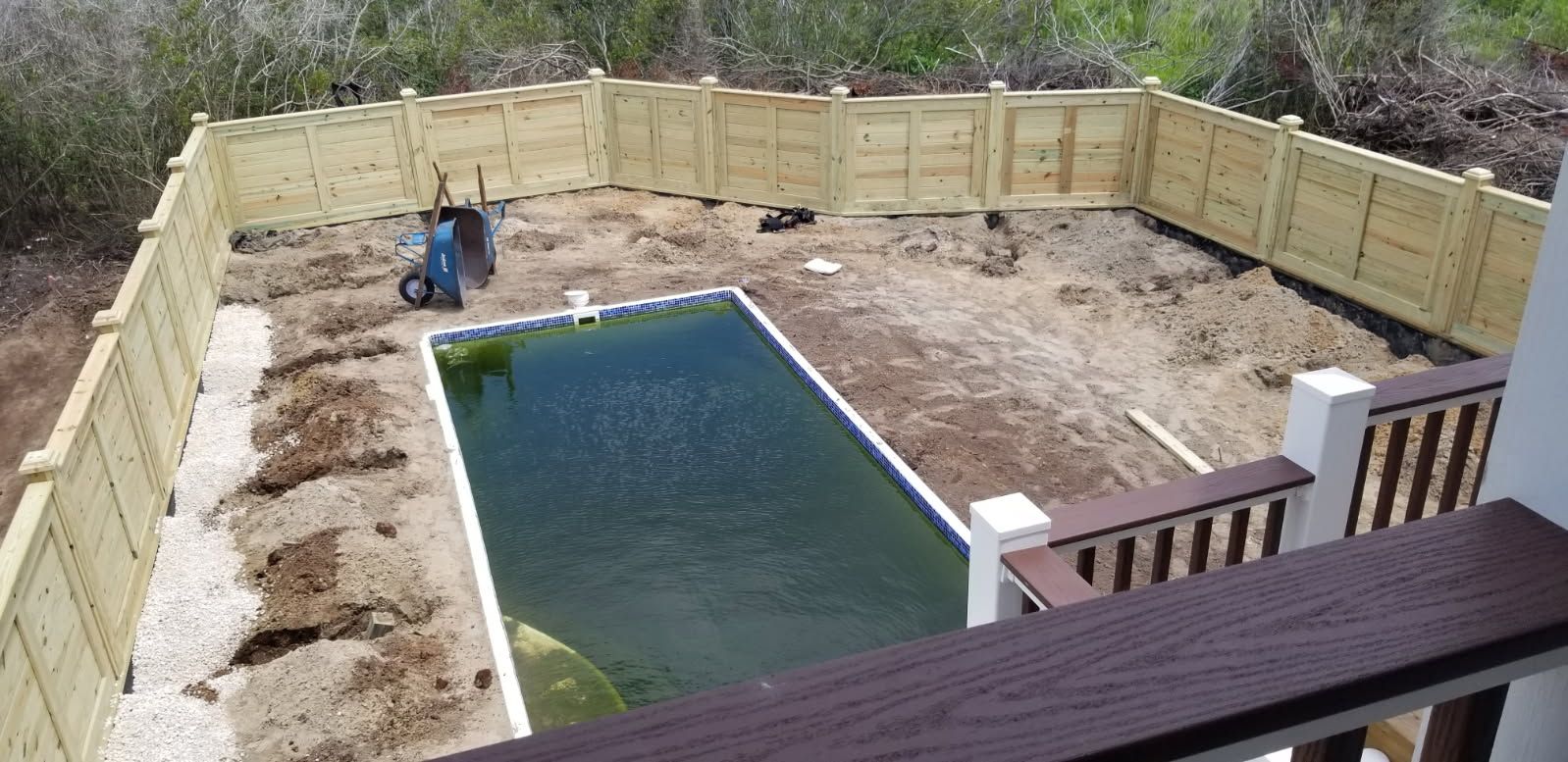 A large swimming pool is surrounded by a wooden fence