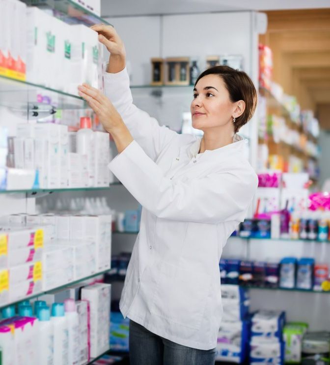 A Woman is Reaching for a Product on a Shelf in a Pharmacy — Northern Beaches GP Superclinic in Deeragun, QLD