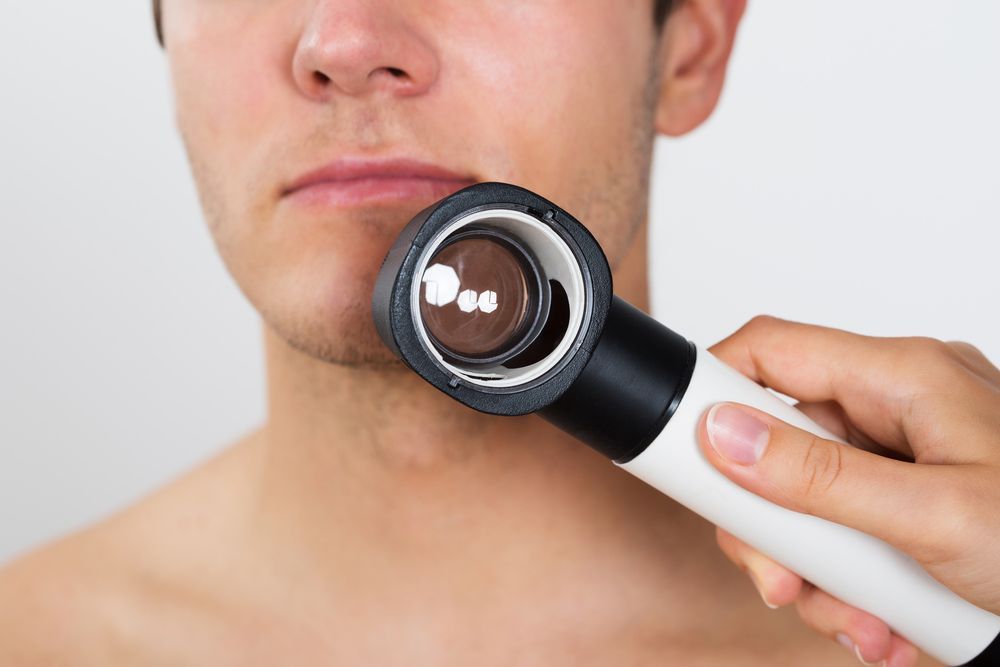 A Man is Being Examined by a Doctor With a Magnifying Glass — Northern Beaches GP Superclinic in Deeragun, QLD
