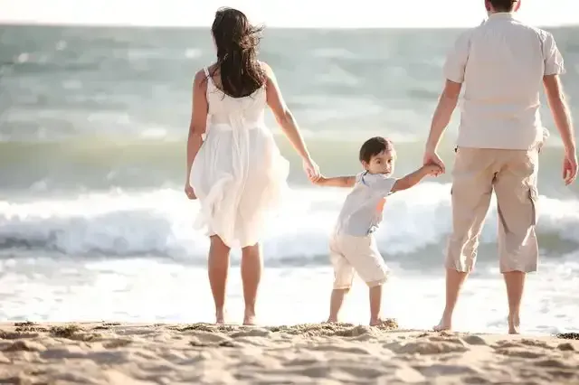 A Family is Walking on the Beach Holding Hands — Northern Beaches GP Superclinic in Townsville, QLD