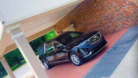 Black SUV parked under a covered entrance beside a brick wall.