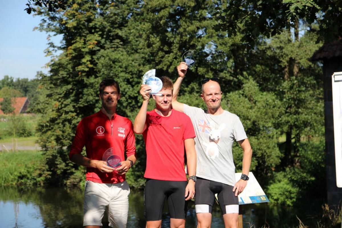Drie mannen staan ​​naast elkaar voor een watermassa.
