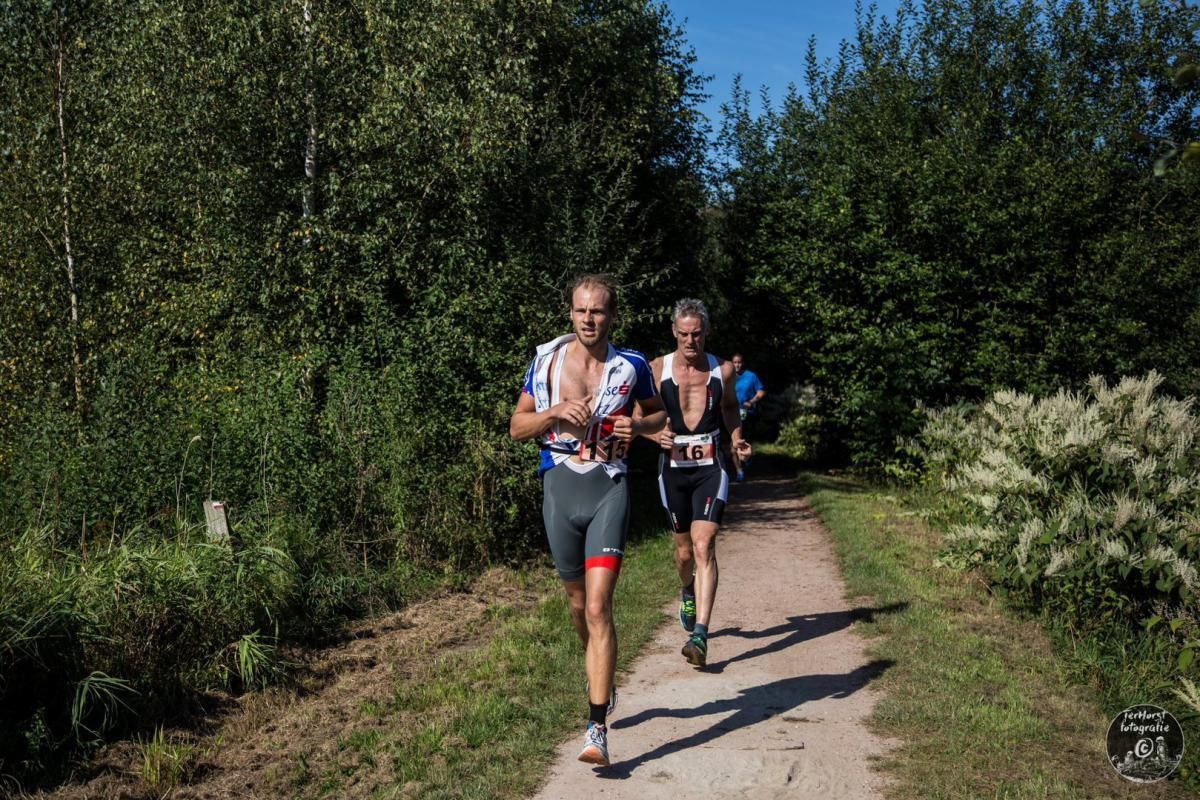 Twee mannen rennen over een pad in het bos.