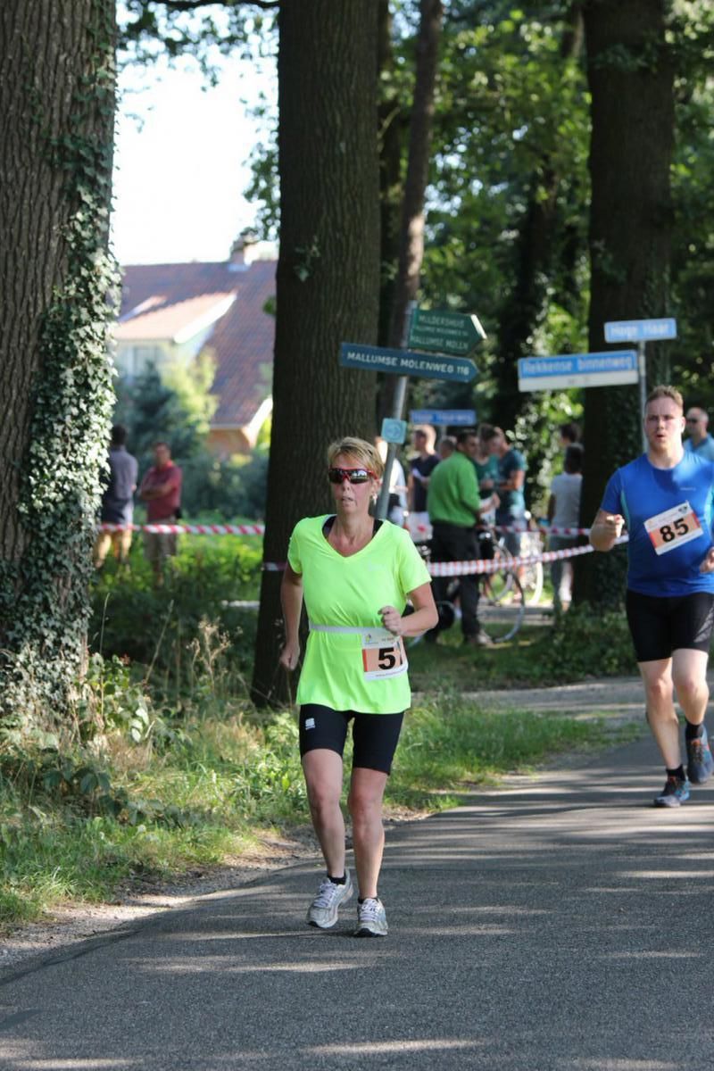 Een vrouw in een neongroen shirt heeft het nummer 5 op haar riem