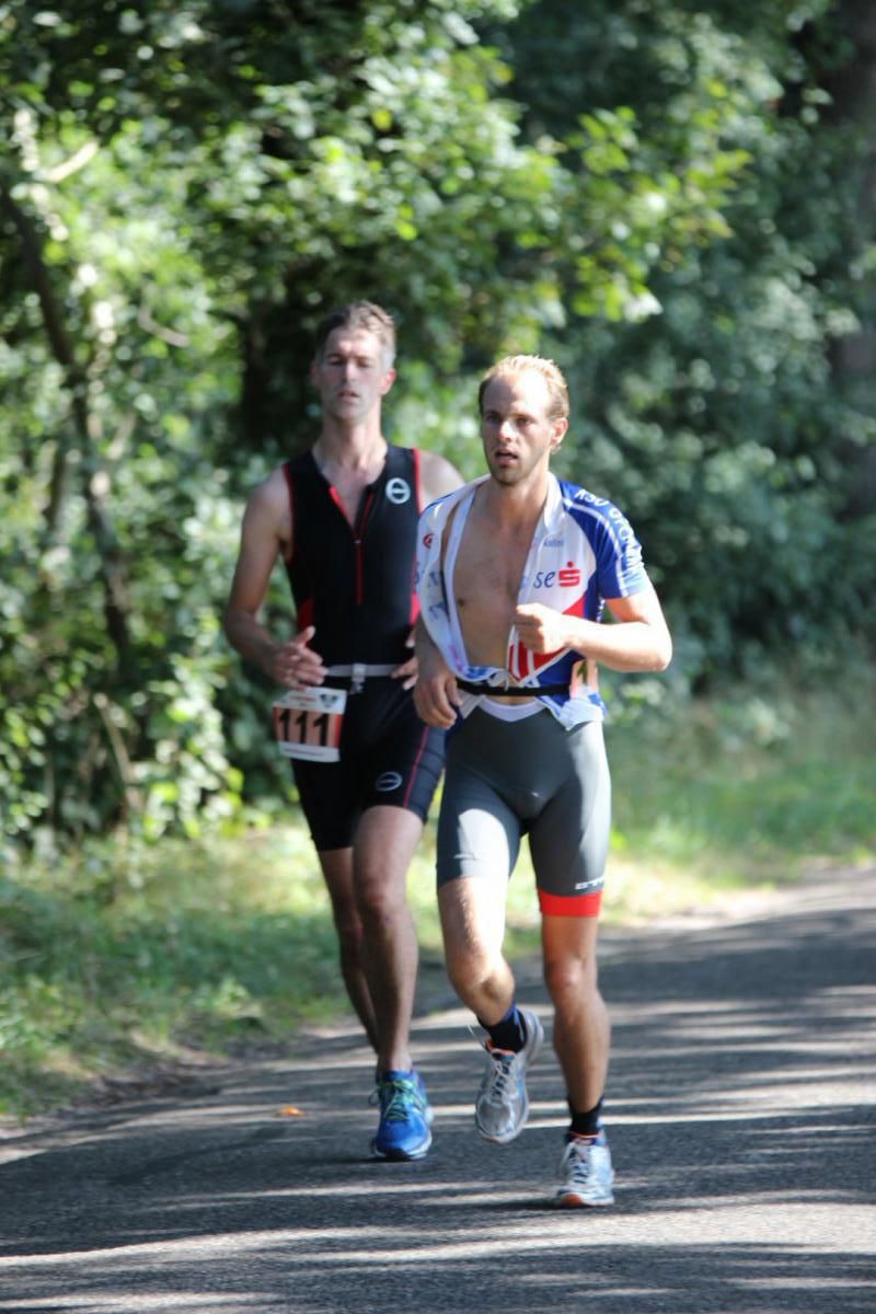 Twee mannen rennen over een weg tijdens een triatlon.