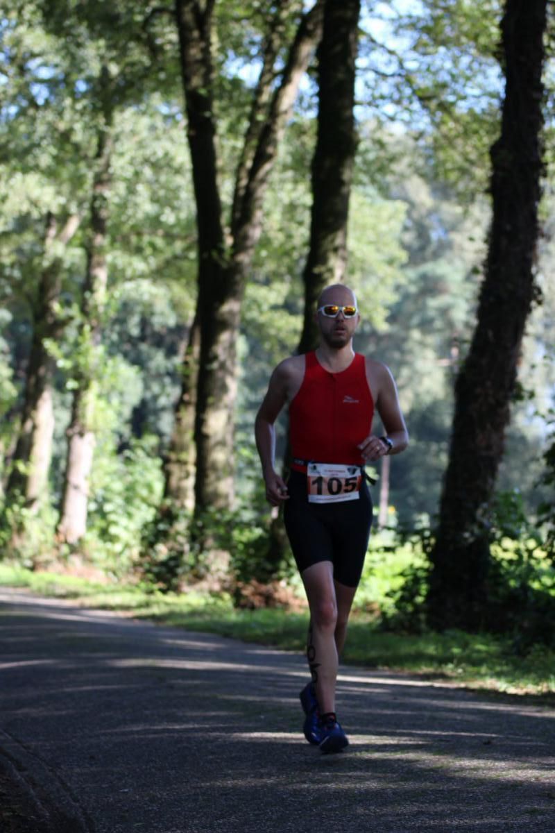 Een man rent over een weg in het bos.