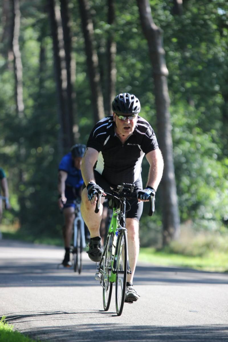 Een man fietst over een weg in het bos.