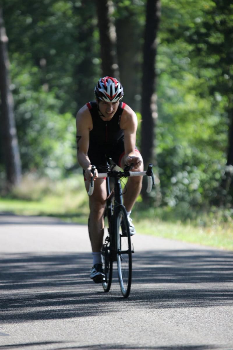 Een man met een helm rijdt op een fiets over een weg