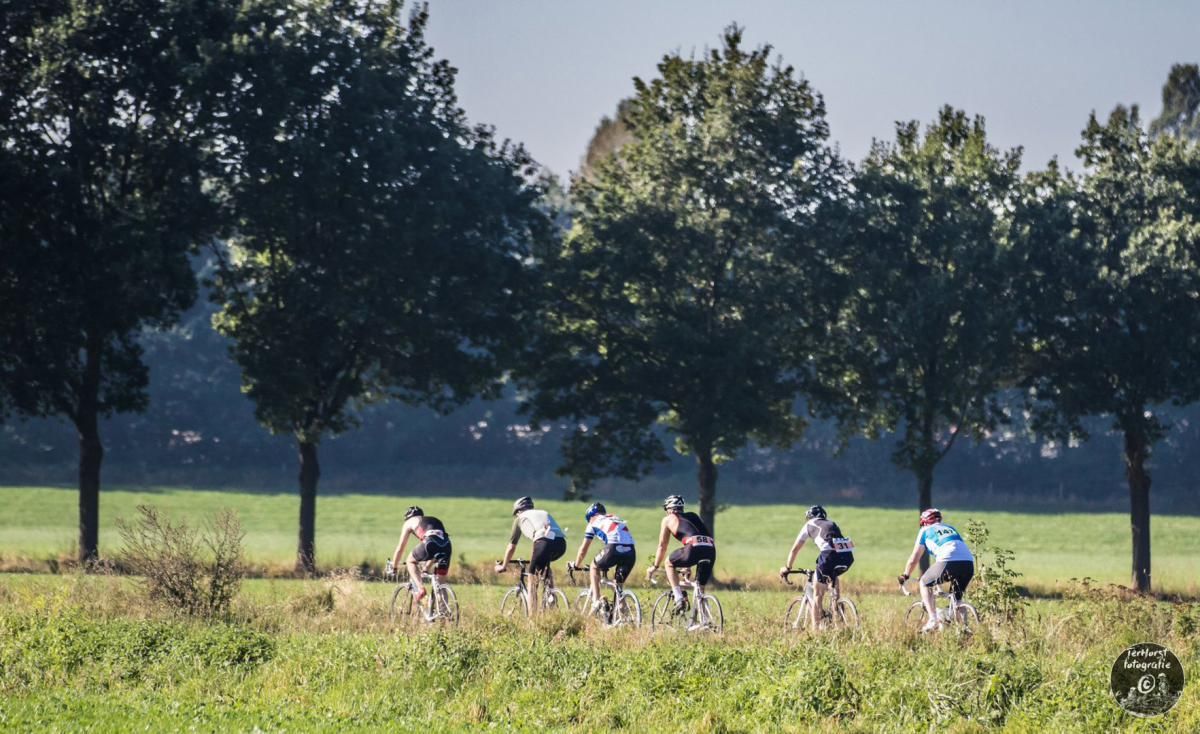 Een groep mensen fietst in een veld.