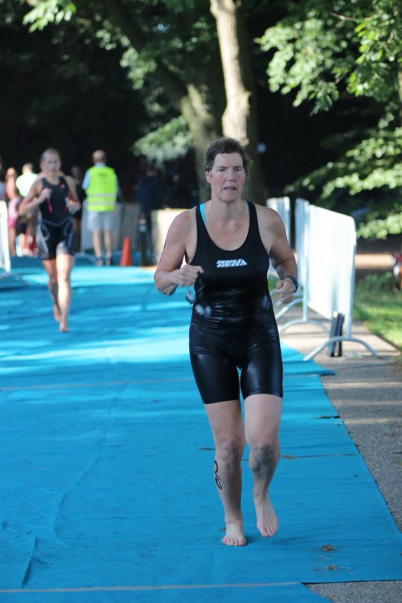 Een vrouw in een wetsuit rent op een blauwe mat