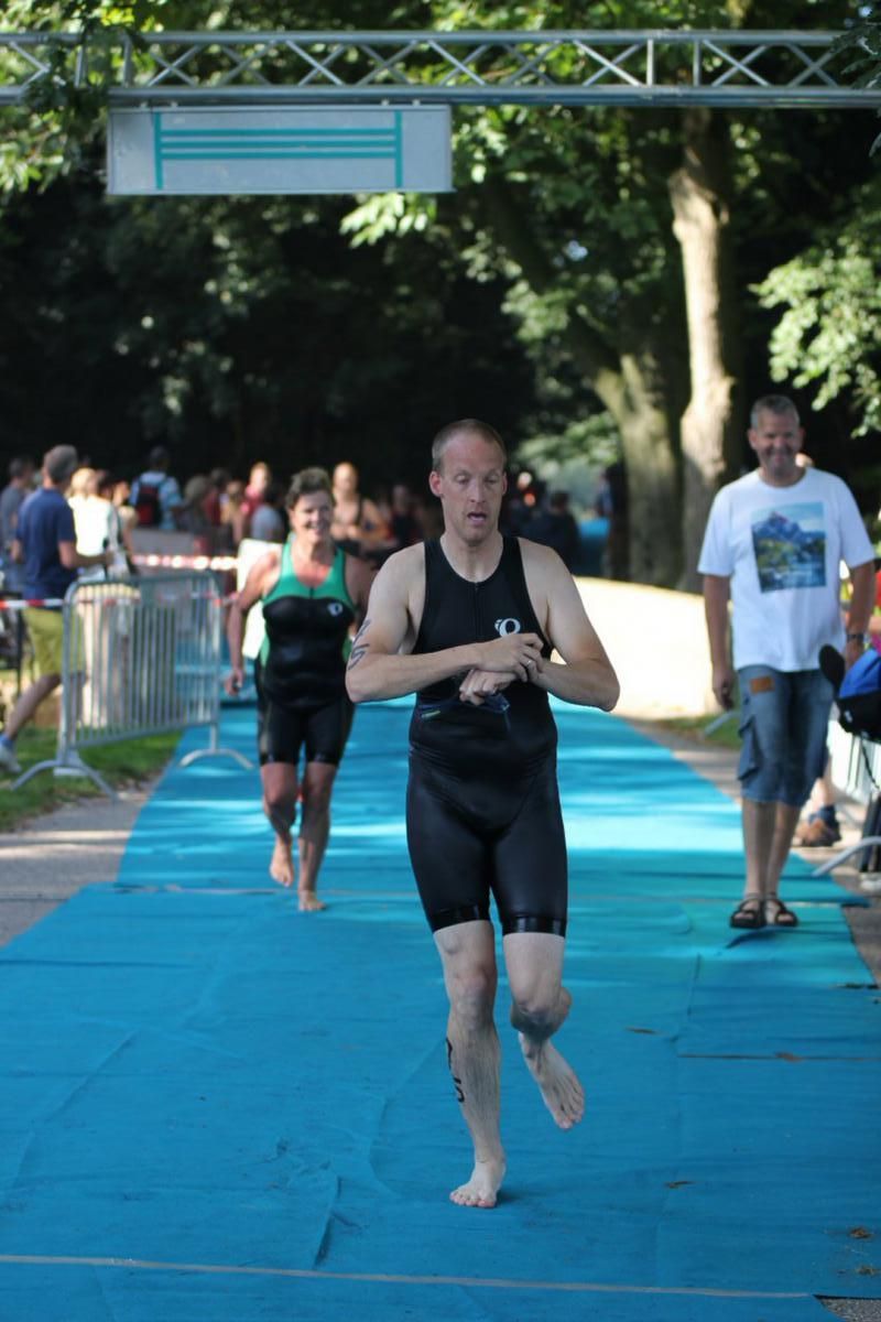 Een man in een wetsuit rent op een blauwe mat