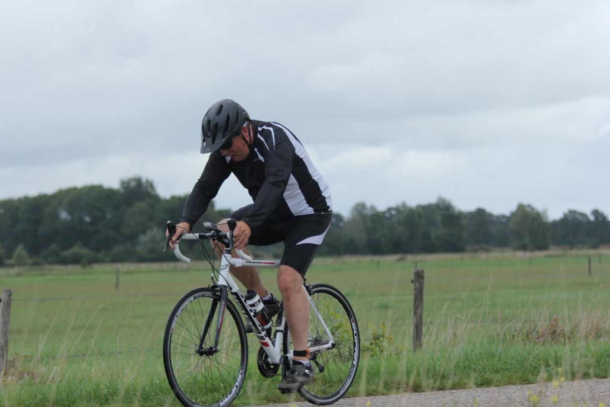 Een man fietst op een weg in een veld.