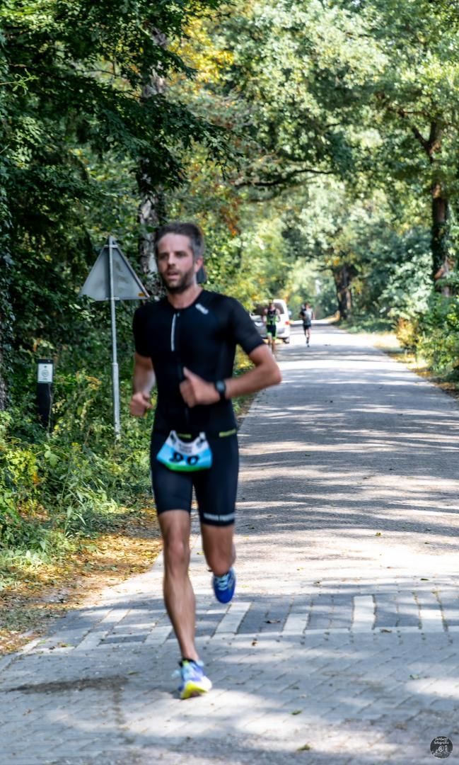 Een man rent over een weg in het bos.